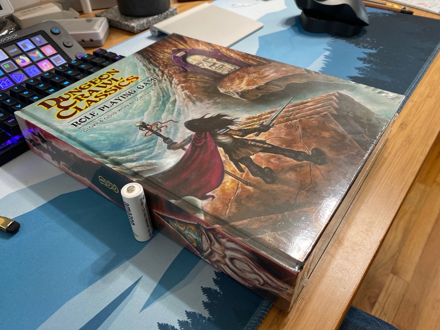a photo of the Dungeon Crawl Classics handbook with a AA battery standing up next to the spine to show how thick the tome is. 